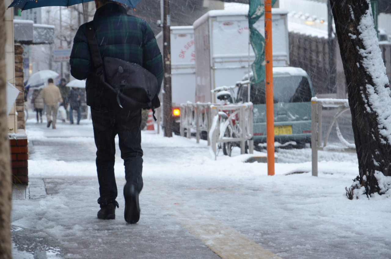 雪が積もった歩道を歩く人